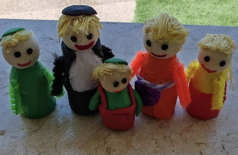 Five small clay family figures with yarn hair